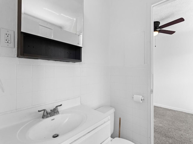 bathroom featuring ceiling fan, tile walls, vanity, a textured ceiling, and toilet