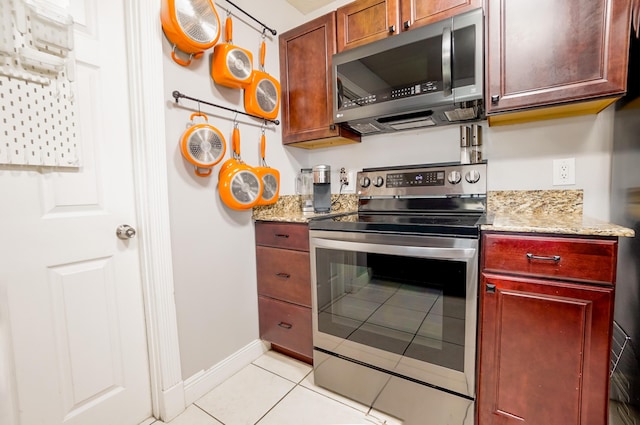 kitchen with light tile patterned flooring, stainless steel appliances, and light stone counters