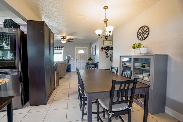 tiled dining room with ceiling fan with notable chandelier and a textured ceiling