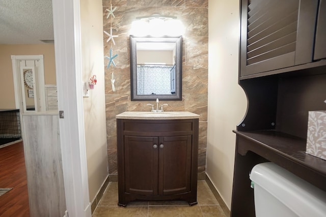 bathroom featuring tile patterned floors, vanity, toilet, and a textured ceiling