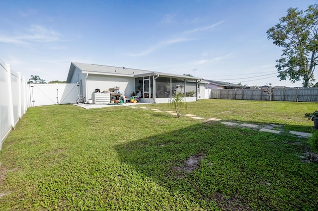 rear view of house featuring a sunroom, a patio area, and a lawn