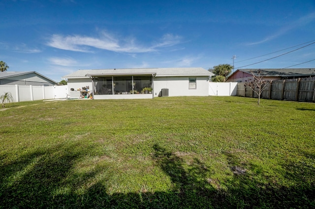 rear view of house featuring a yard, a sunroom, and central air condition unit