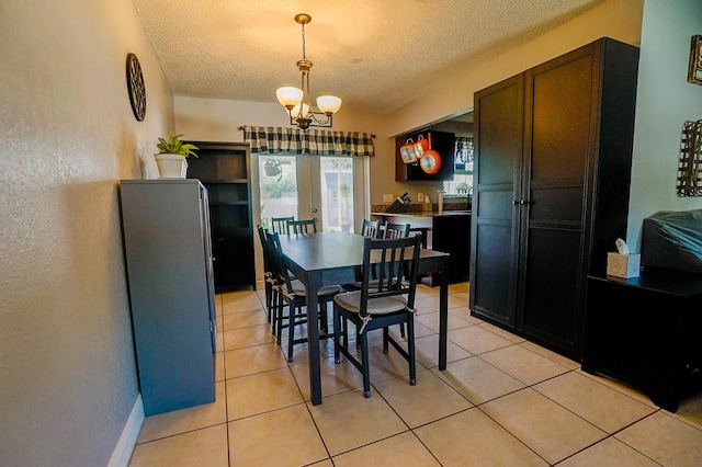 dining space with light tile patterned floors, a chandelier, french doors, and a textured ceiling