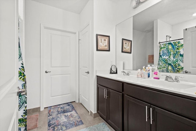 bathroom with double vanity, curtained shower, tile patterned flooring, and a sink