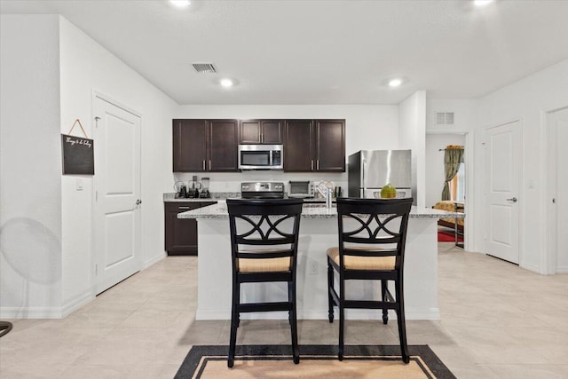 kitchen featuring dark brown cabinetry, a kitchen island with sink, visible vents, and stainless steel appliances