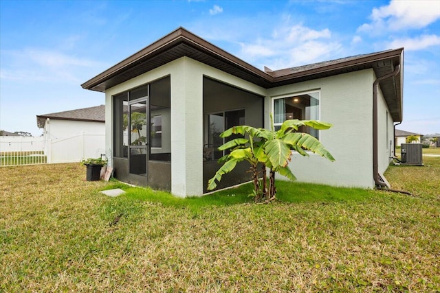 back of house with a yard, stucco siding, a sunroom, central AC, and fence