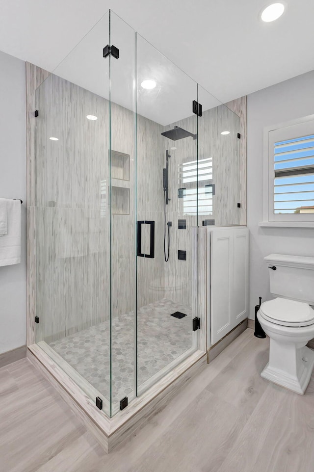 bathroom featuring toilet, hardwood / wood-style floors, and a shower with shower door