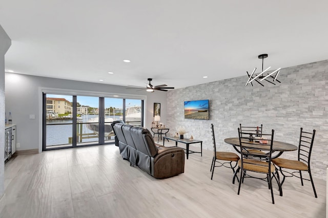 living room with ceiling fan with notable chandelier and light wood-type flooring