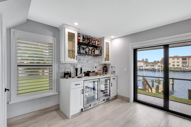 bar with plenty of natural light, white cabinets, and a water view