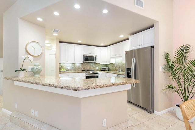 kitchen with sink, appliances with stainless steel finishes, white cabinets, light stone countertops, and backsplash