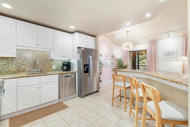 kitchen with sink, white cabinetry, stainless steel appliances, light stone countertops, and backsplash