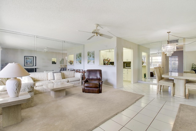 living room with ceiling fan with notable chandelier, a textured ceiling, and light tile patterned floors