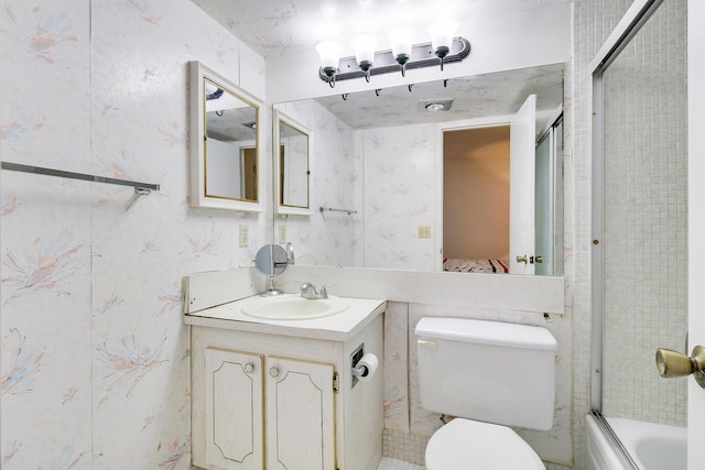 full bathroom with enclosed tub / shower combo, vanity, and toilet