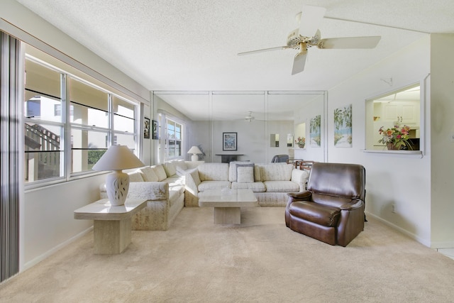 living room featuring ceiling fan, light colored carpet, and a textured ceiling