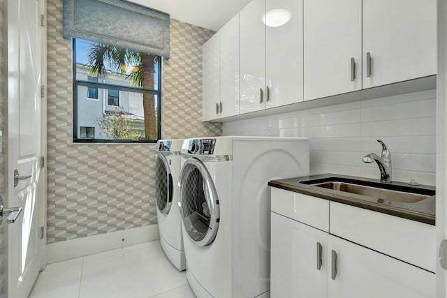 washroom featuring cabinets, sink, light tile patterned floors, and washer and clothes dryer