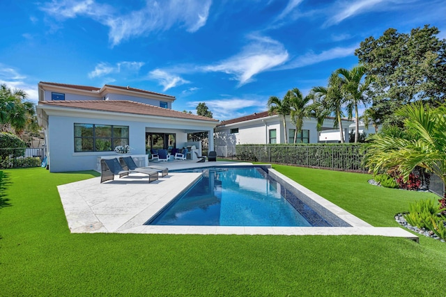 rear view of house with a fenced in pool, a lawn, and a patio area