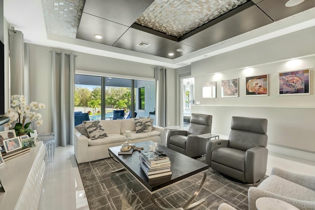 living room with a raised ceiling and dark tile patterned flooring