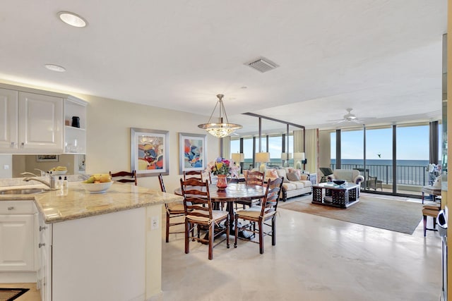 dining room with expansive windows, a healthy amount of sunlight, a water view, and sink