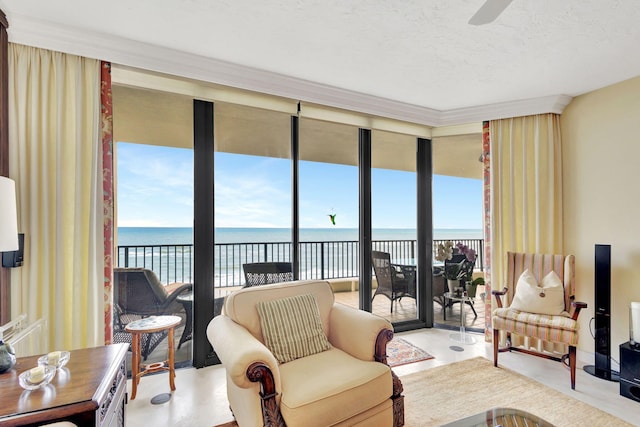 living room with a water view, a wall of windows, crown molding, and a textured ceiling