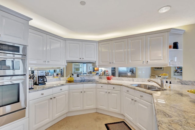 kitchen featuring stainless steel double oven, sink, and white cabinets