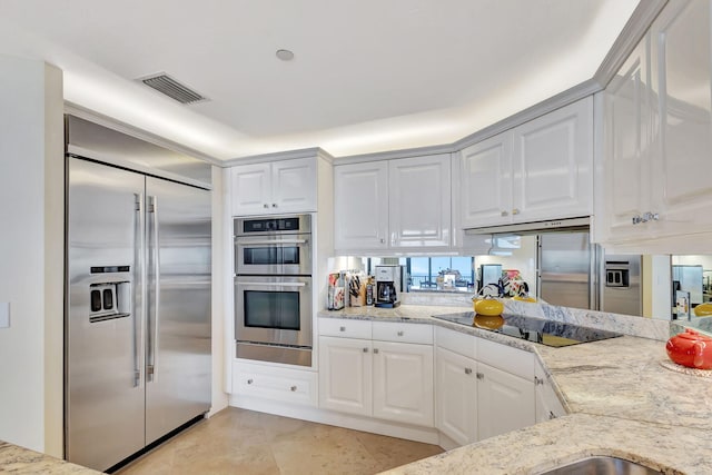 kitchen with light stone countertops, white cabinetry, and appliances with stainless steel finishes