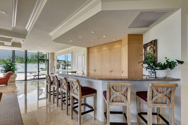 kitchen with stone countertops, expansive windows, light tile patterned floors, kitchen peninsula, and light brown cabinets