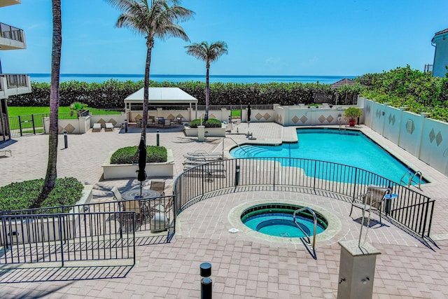 view of pool with a gazebo, a patio area, an in ground hot tub, and a water view