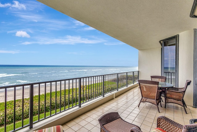 balcony with a water view and a view of the beach