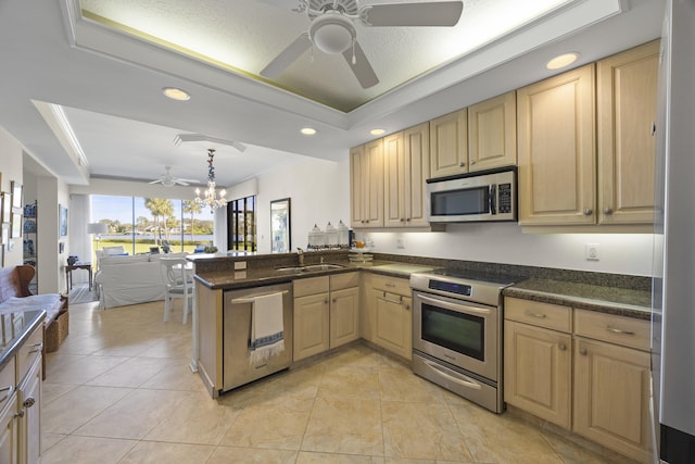 kitchen featuring decorative light fixtures, a tray ceiling, stainless steel appliances, and kitchen peninsula