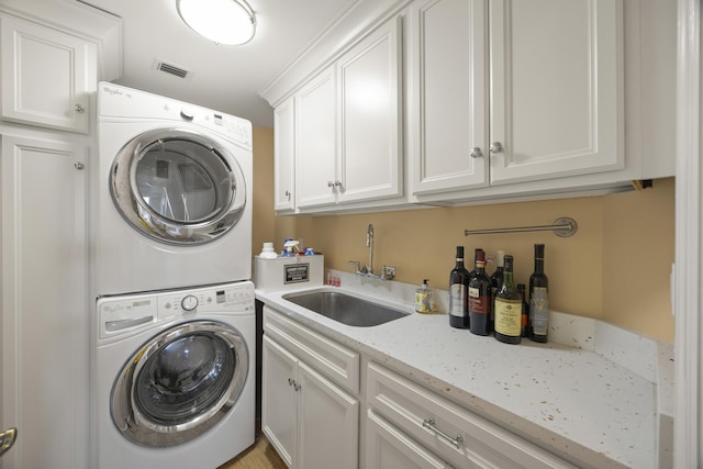 clothes washing area with stacked washer and dryer, sink, and cabinets