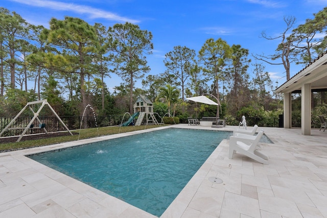 view of swimming pool with a patio area, pool water feature, and a playground