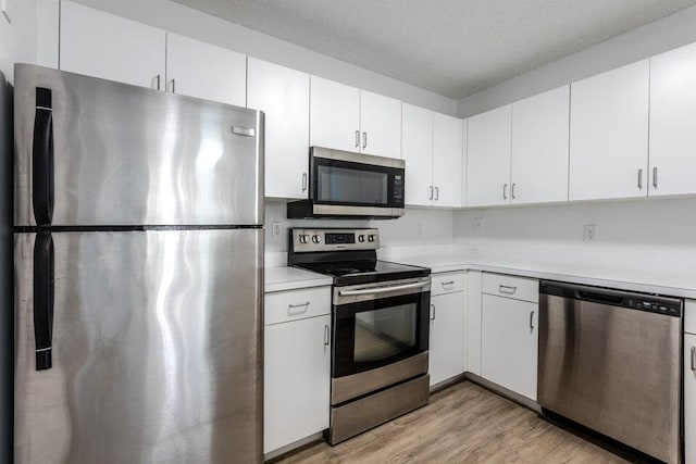 kitchen featuring a textured ceiling, stainless steel appliances, white cabinets, and light wood-type flooring