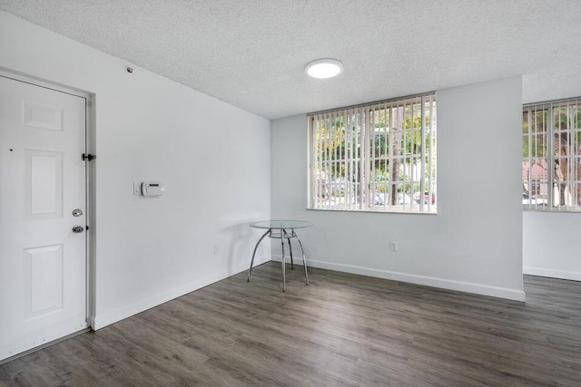 empty room with dark hardwood / wood-style floors and a textured ceiling