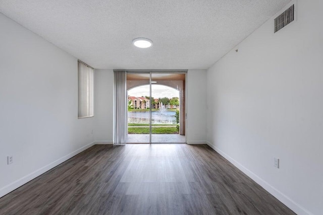 spare room featuring floor to ceiling windows, dark hardwood / wood-style flooring, and a textured ceiling