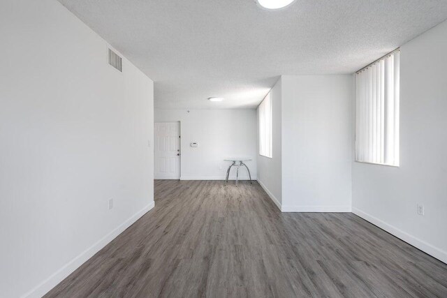 empty room featuring dark hardwood / wood-style flooring and a textured ceiling