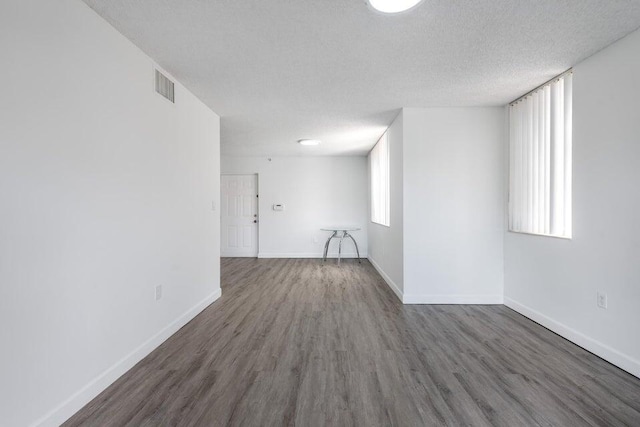 unfurnished room featuring a healthy amount of sunlight, dark wood-type flooring, and a textured ceiling