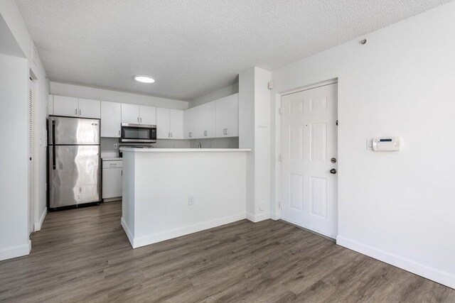 unfurnished room featuring a textured ceiling, dark hardwood / wood-style floors, and a healthy amount of sunlight