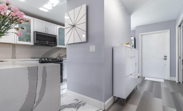 kitchen with white cabinets, stainless steel appliances, and light stone counters