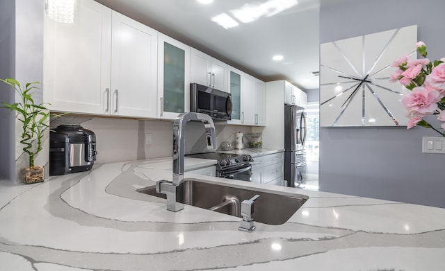 kitchen with white cabinetry, light stone countertops, and appliances with stainless steel finishes