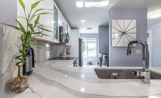 kitchen featuring white cabinets, washing machine and clothes dryer, appliances with stainless steel finishes, and sink