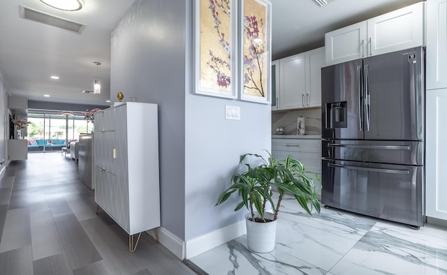 kitchen featuring white cabinets, decorative backsplash, stainless steel fridge, and pendant lighting