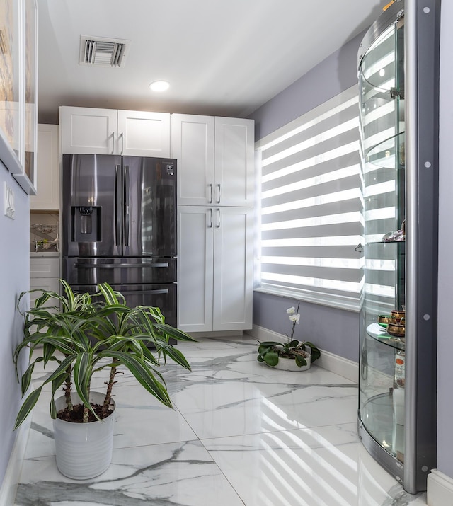 kitchen with white cabinets, light stone countertops, and fridge with ice dispenser