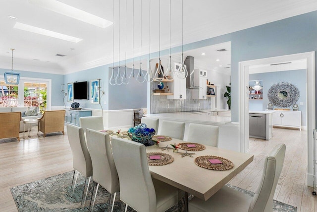 dining space with crown molding, light wood-type flooring, and a skylight