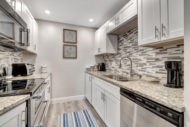 kitchen with light stone counters, sink, stainless steel appliances, and white cabinets