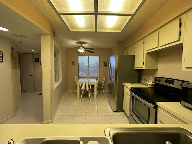 kitchen featuring ceiling fan, white cabinets, stainless steel appliances, and light tile patterned flooring