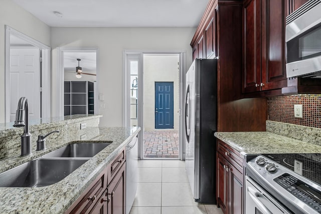 kitchen featuring tasteful backsplash, sink, light tile patterned floors, stainless steel appliances, and light stone countertops