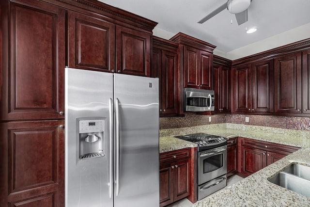 kitchen with light stone countertops, appliances with stainless steel finishes, backsplash, and ceiling fan