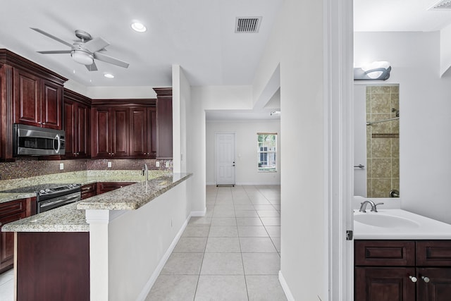 kitchen featuring light tile patterned flooring, sink, light stone counters, stainless steel appliances, and backsplash