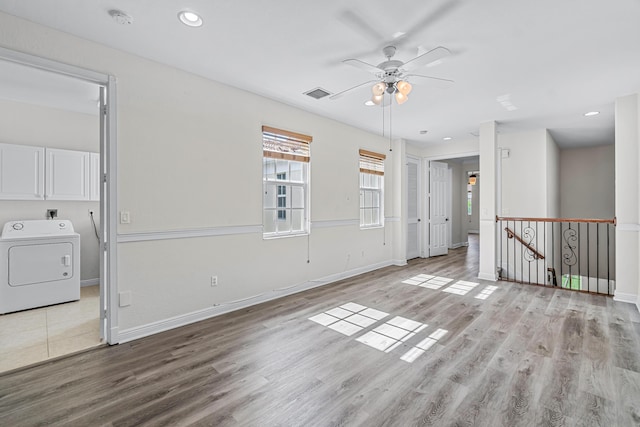 spare room featuring washer / dryer, ceiling fan, and light wood-type flooring