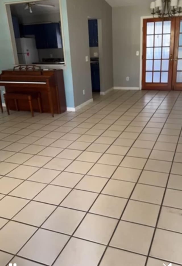 unfurnished living room with french doors, a chandelier, and light tile patterned floors